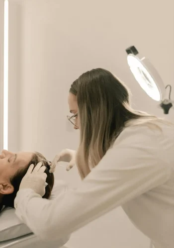 Dermatologist performing a treatment in a clinic setting with specialized equipment.